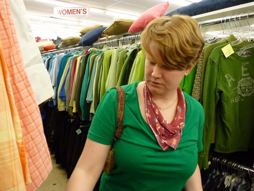 A woman walking through the aisles of a thrift shop