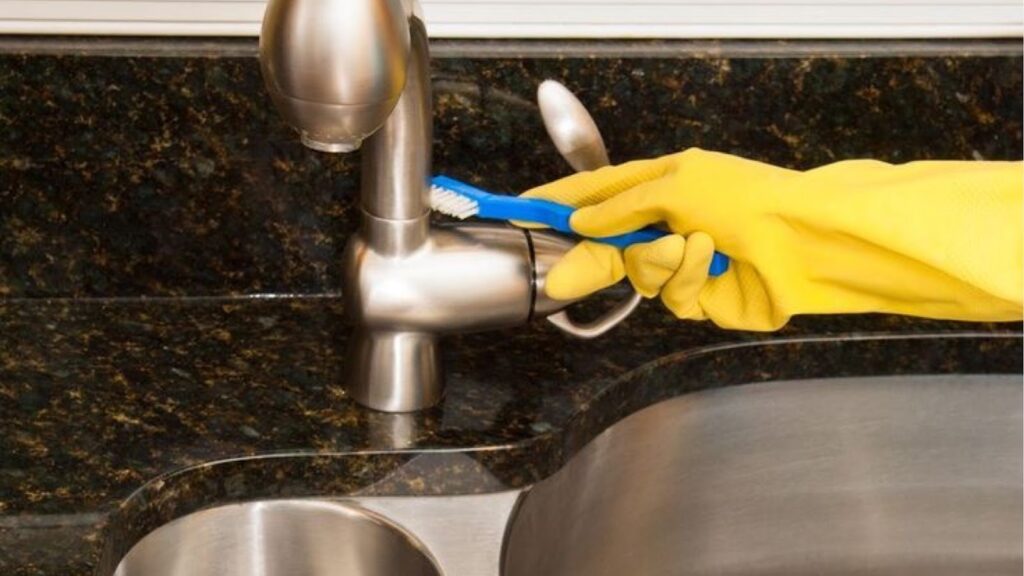 Person cleaning corners and edges with old toothbrush