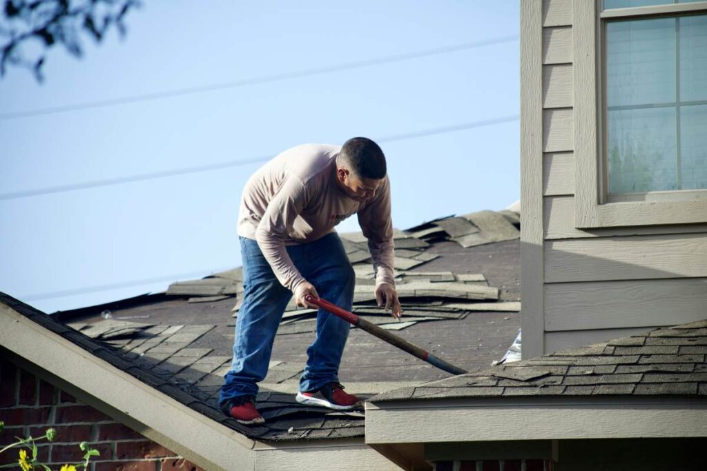 A man trying to remove roof tiles