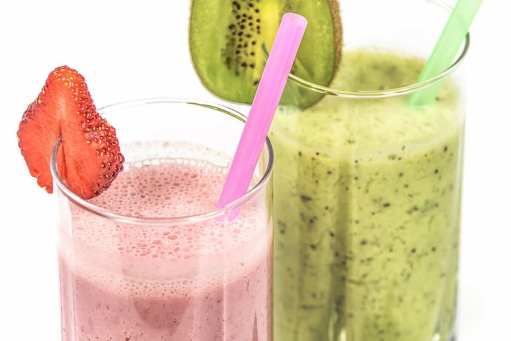 Strawberry and Kiwi milkshake on drinking glass and straws