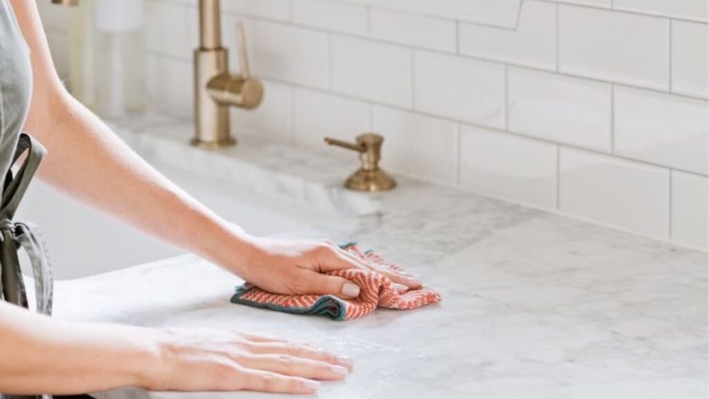 Woman drying sink with a microfiber towel