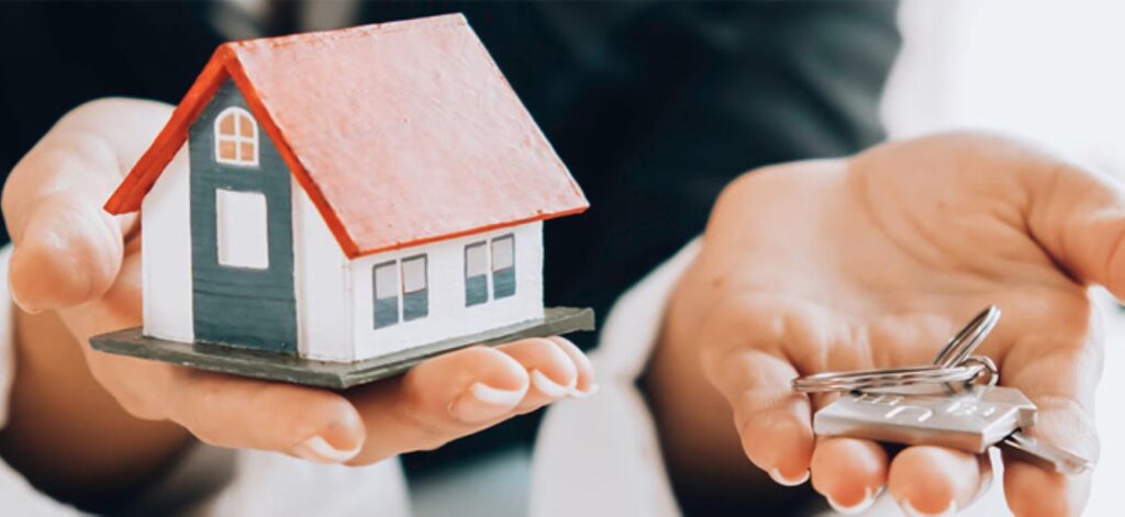 Someone holding a model house and a bunch of keys