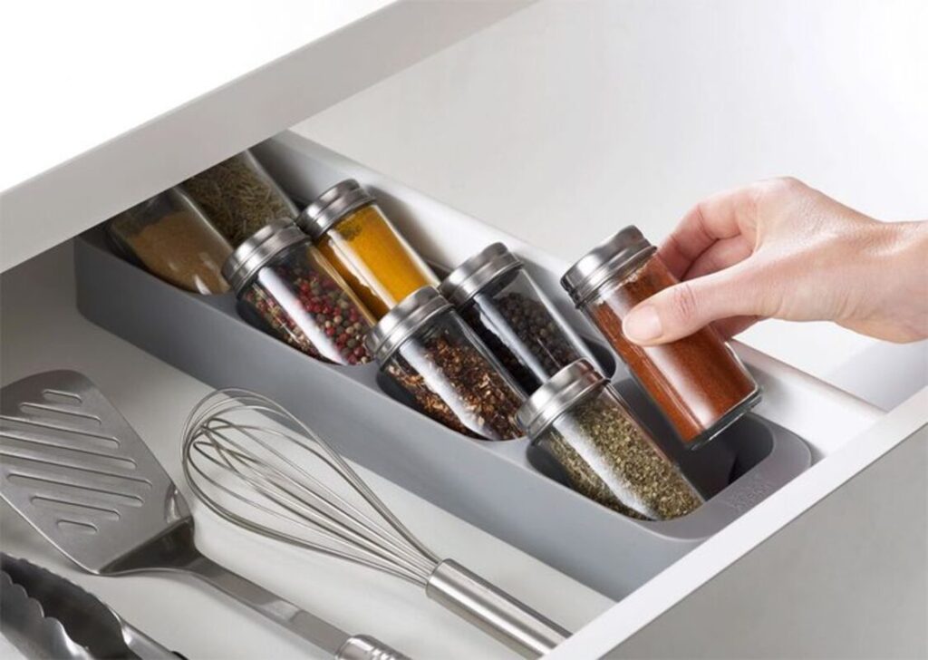 A drawer with jars of spices and other kitchen utensils