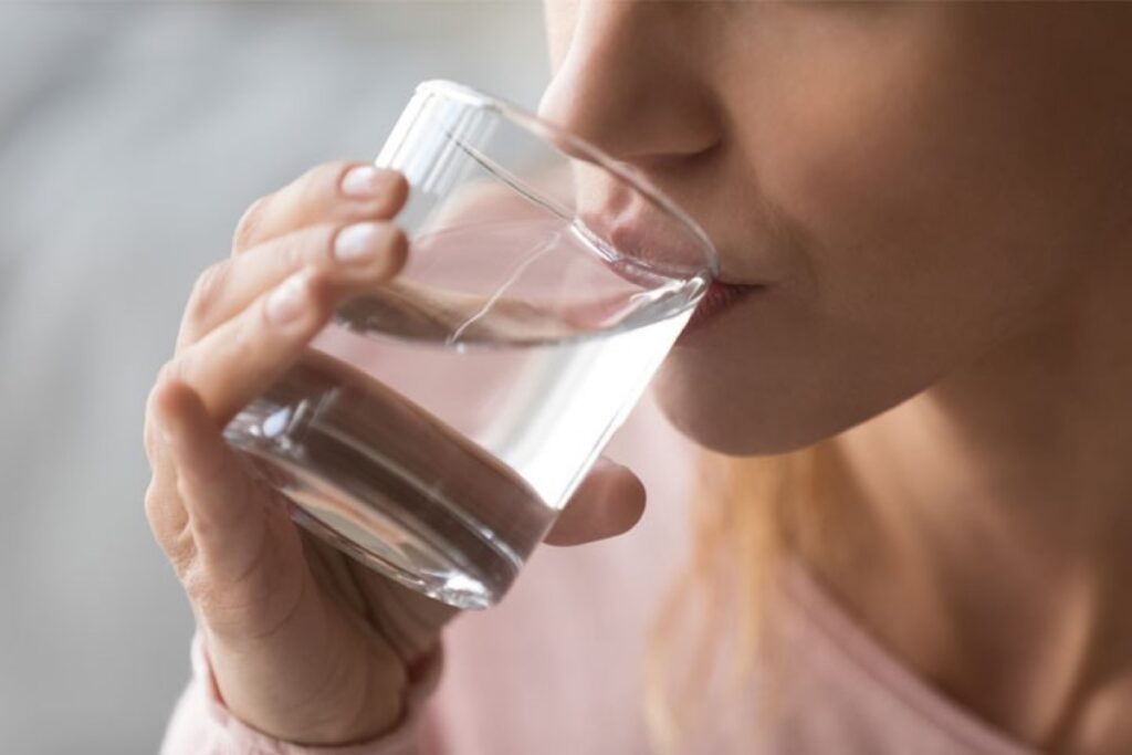 A woman drinking water from a glass cup