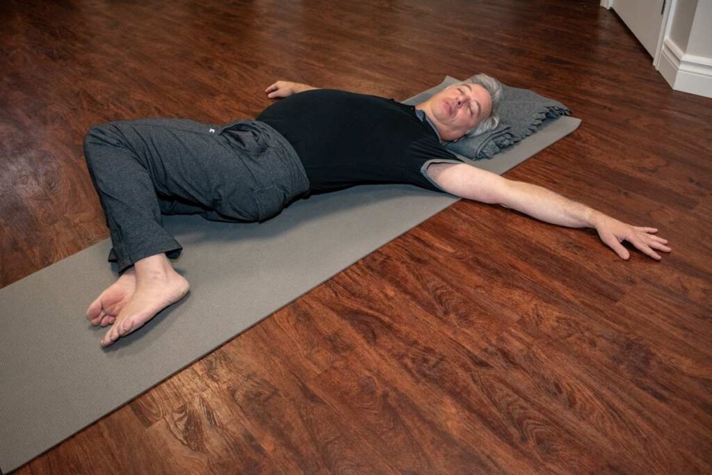 Elderly man doing a supine twist routine