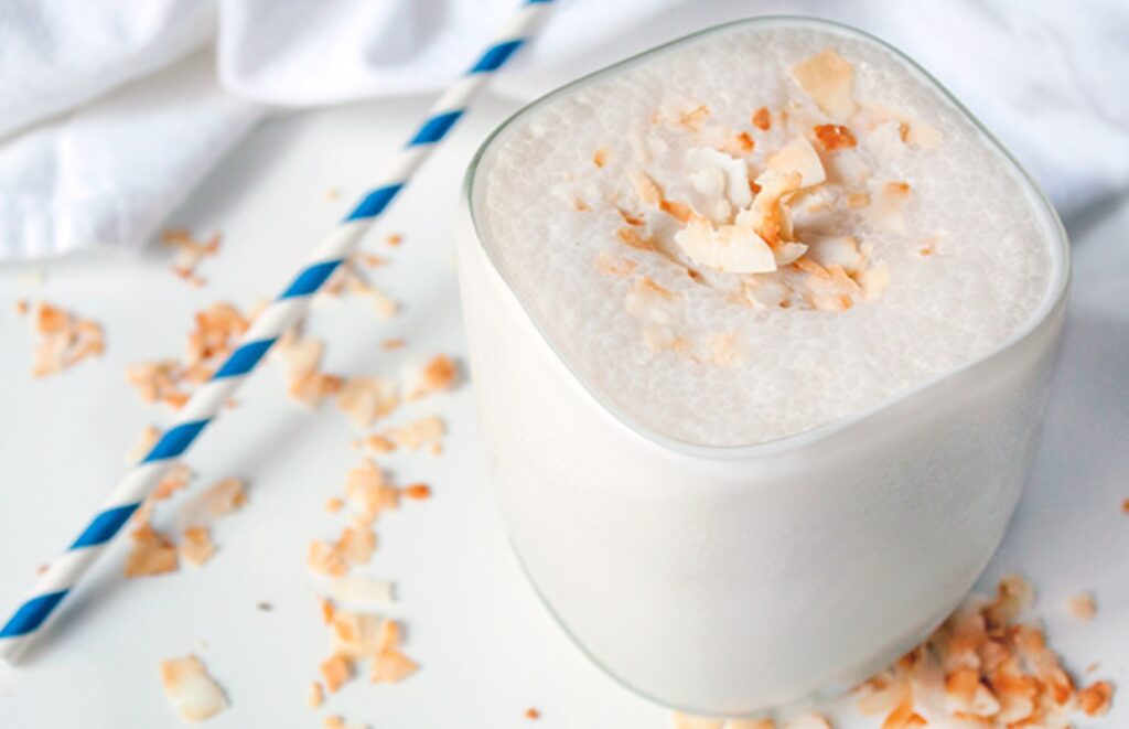 Protein shake served in glass cup with sprinkles of toasted coconut