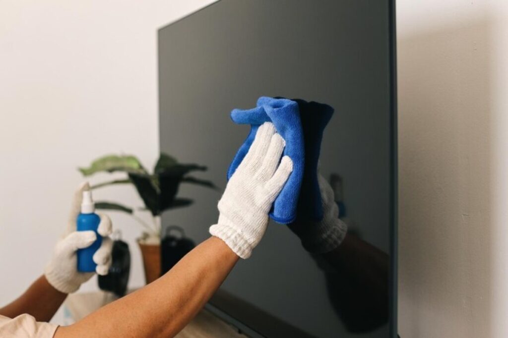 Closeup of hand cleaning TV screen surfaces