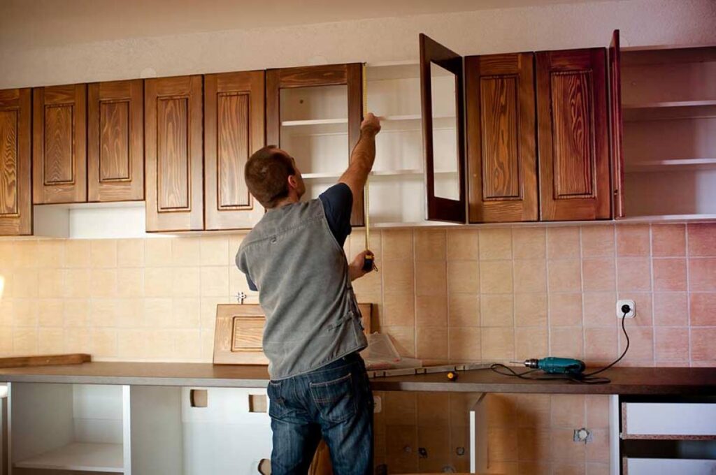 A man repairing some cabinet doors