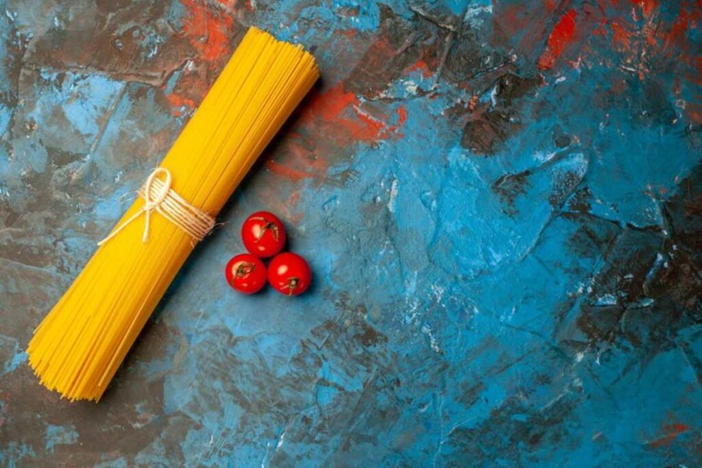 Overhead view of angel hair pasta tied with rope and tomatoes