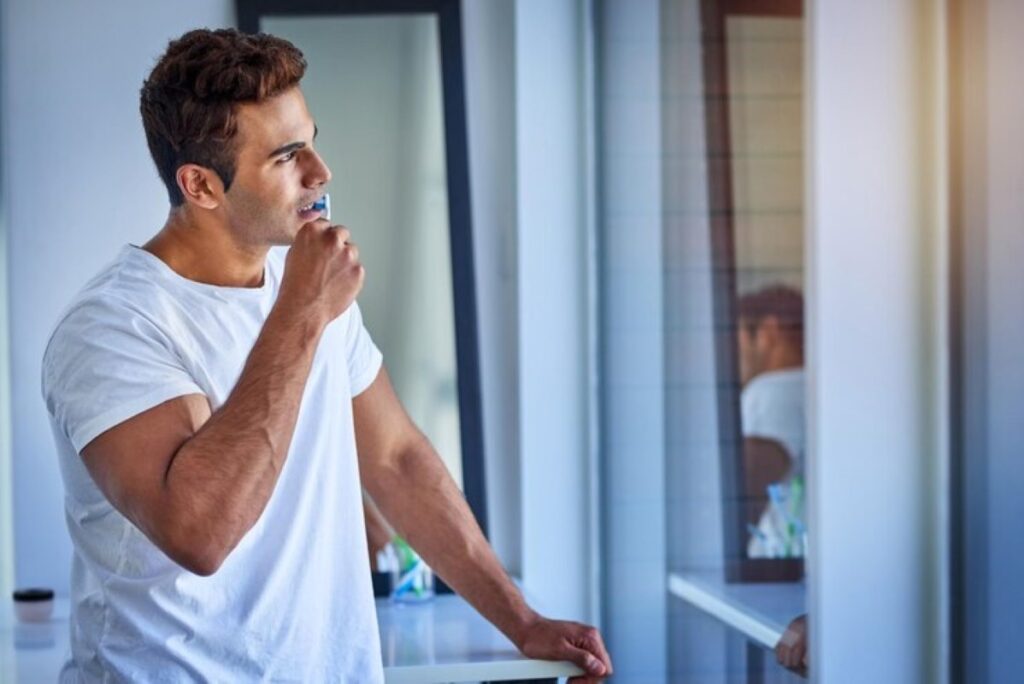 Shot of a handsome young man looking thoughtful while brushing his teeth at home