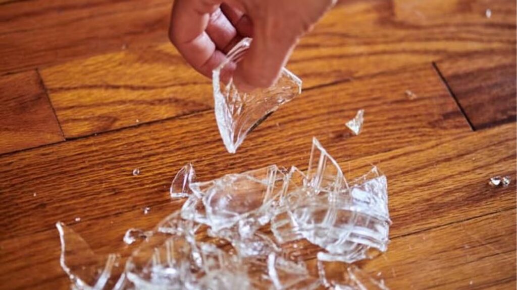 Person packing up broken glass on the floor