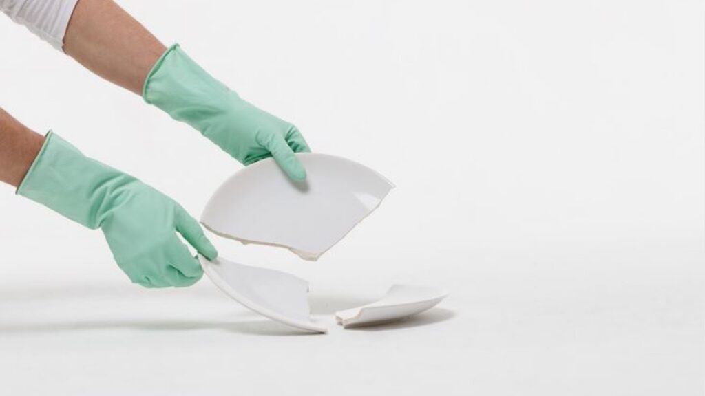 Person Picking up a broken plate with gloves on