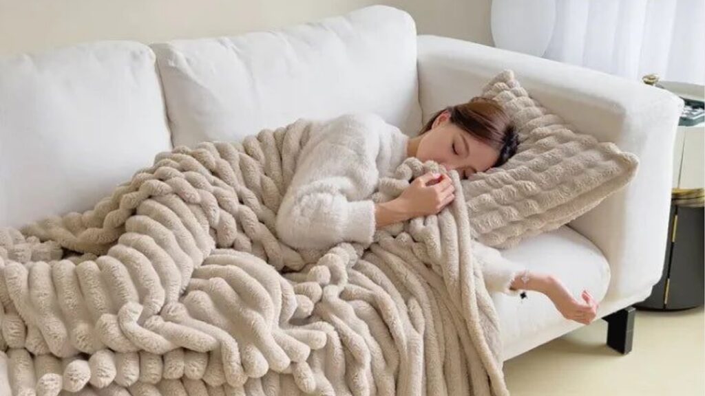 A woman cuddled up in a throw blanket